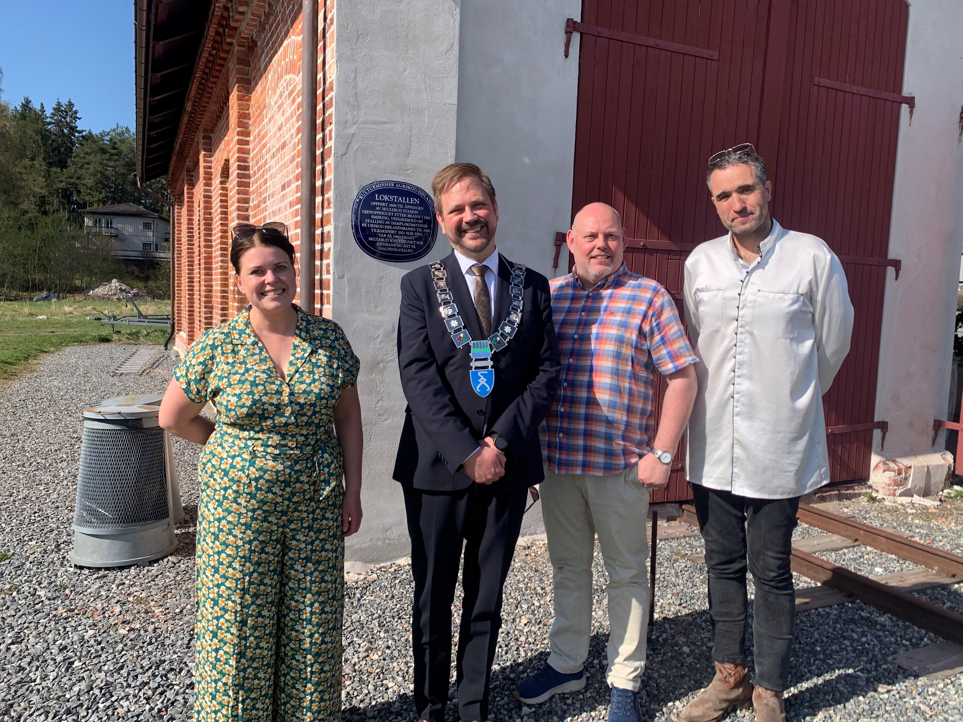 Fire personer foran blått skilt