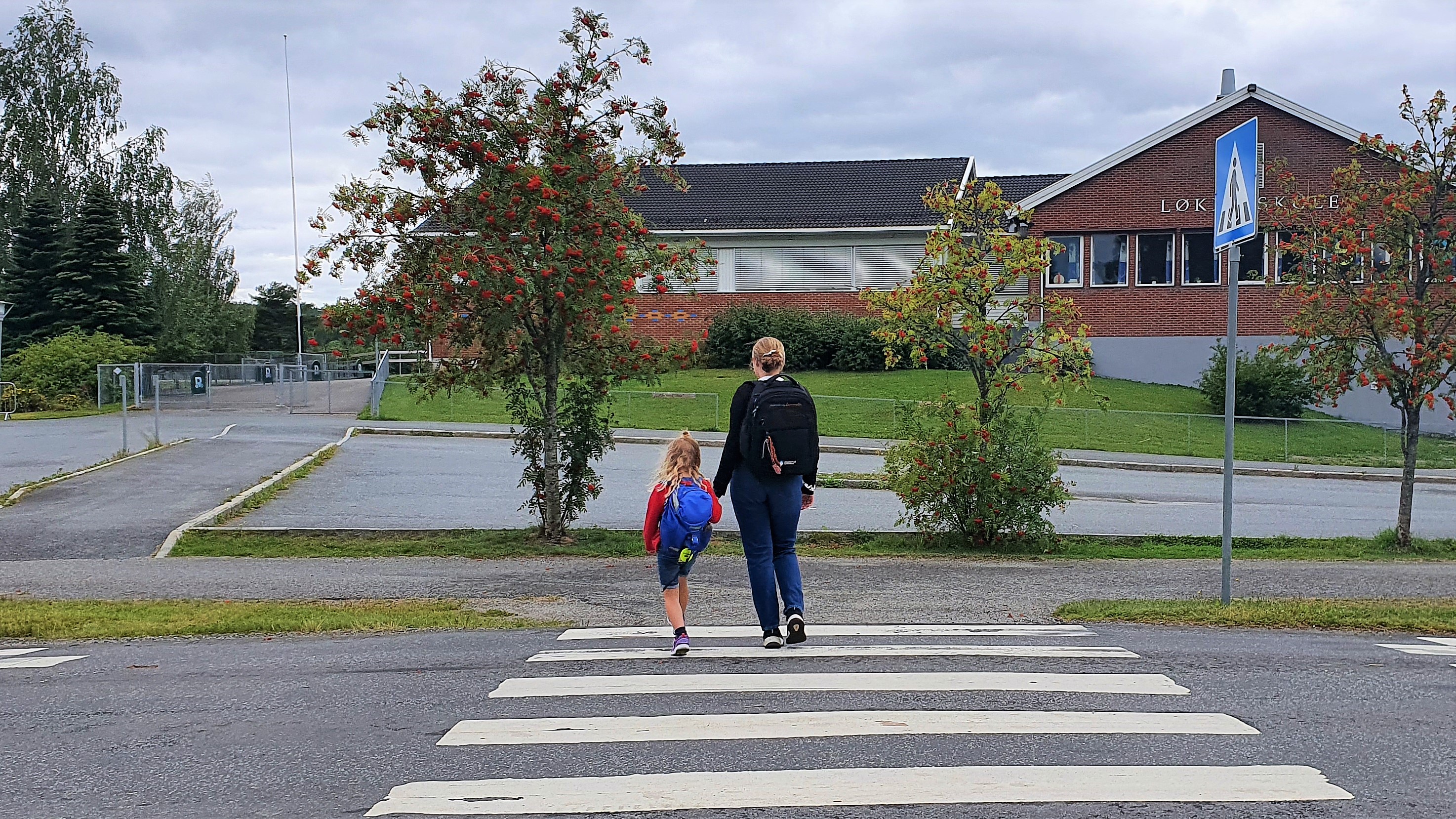 To barn som krysser veien ved en skole. 